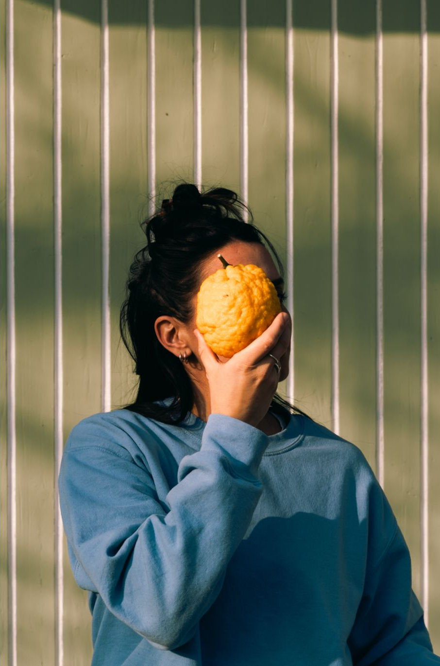 Una donna tiene un grande agrume giallo davanti al viso